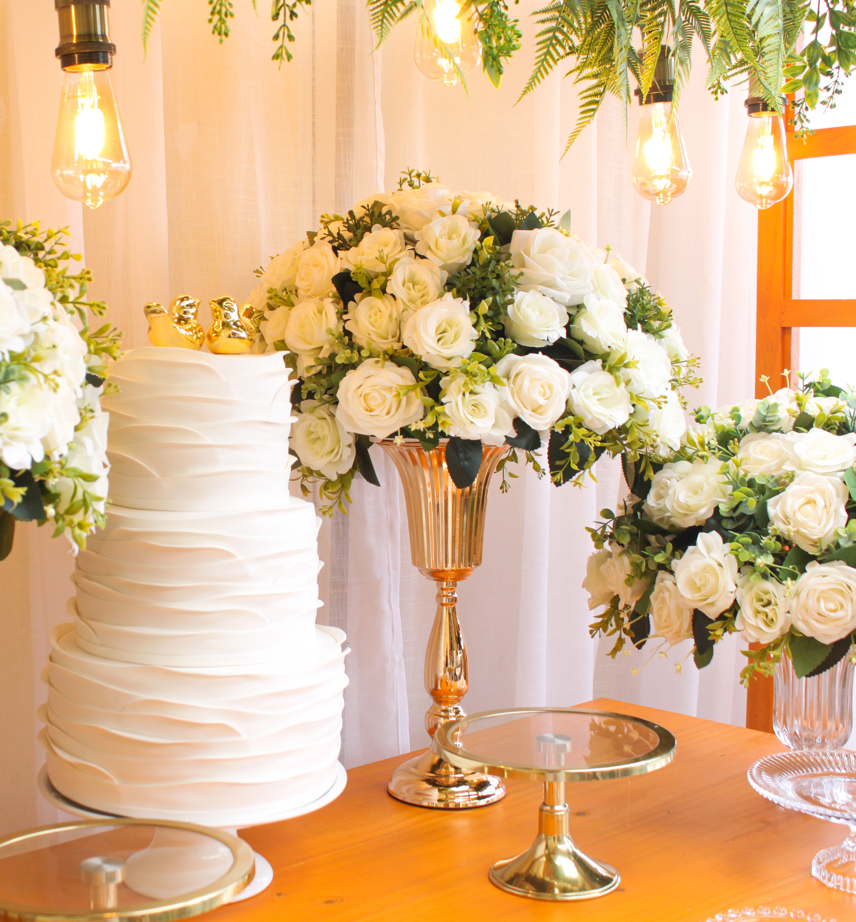 Arranjo de flores clássico e simétrico para casamento, com formato arredondado tradicional composto por rosas brancas e folhagens organizadas de forma harmônica.